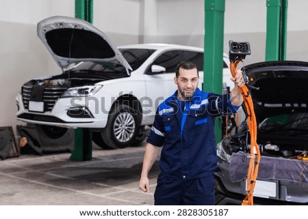 Professional EV technician presenting a high-voltage charging cable connector inside a modern electric vehicle service workshop. 