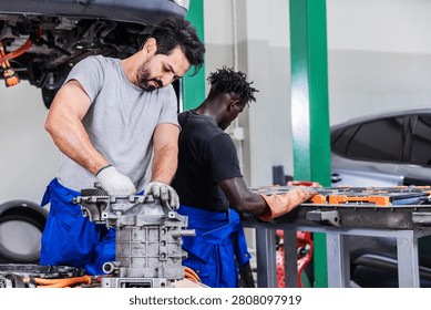 Professional EV technicians performing electric drive unit repair and high-voltage battery maintenance in a modern electric vehicle service workshop. The team works simultaneously on powertrain components and battery systems, demonstrating technical expertise, teamwork, automotive engineering, preventive maintenance, and sustainable electric mobility.