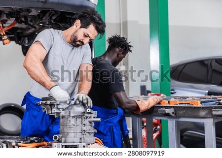 Professional EV technicians performing electric drive unit repair and high-voltage battery maintenance in a modern electric vehicle service workshop. The team works simultaneously on powertrain components and battery systems, demonstrating technical expertise, teamwork, automotive engineering, preventive maintenance, and sustainable electric mobility.