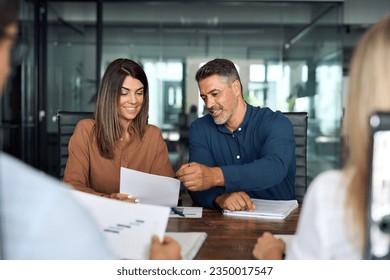 Professional executives business group working with documents at meeting in office. Smiling corporate board team having discussion planning company project strategy sitting at board room table.