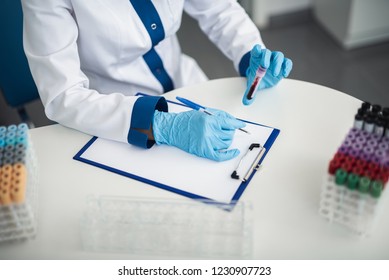 Professional Facility Research In Healthcare System. Top View Of Female Laboratory Worker In Medical Uniform Studying Blood Samples In Lab Office