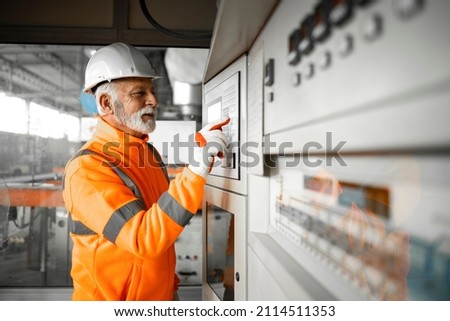 Professional factory worker engineer setting parameters on industrial machines for production or manufacturing.