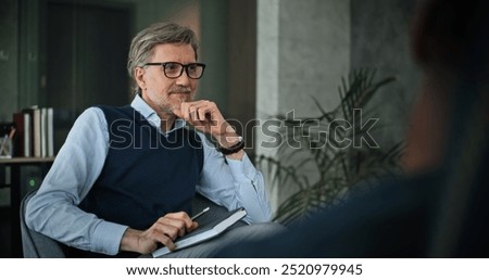 Professional family psychologist sits in chair, talks and listens attentively to patients during counseling session. Mature therapist analyzes problem, conducts group therapy for couple. Psychology.