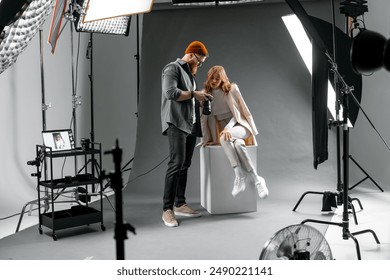 Professional Fashion Photoshoot: Photographer Adjusting Model's Pose in Studio Light Setup - Powered by Shutterstock