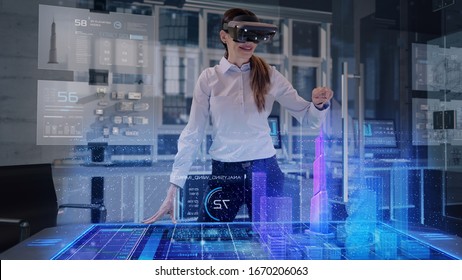 Professional Female Architect Wearing Augmented Reality Headset Makes Gestures And Redesigns 3D City Model. High Tech Office Use Virtual Reality Holographic Modeling Software Application.