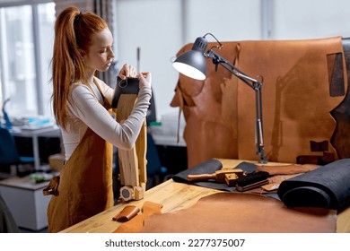 professional female artisan working on Leather Stitching Clam side view shot.handmade technique, active ginger beautiful girl creating her own wallet - Powered by Shutterstock