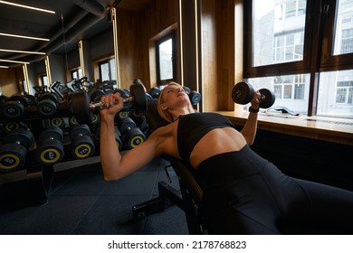 Professional Female Athlete Training With Hand Weights At Gym