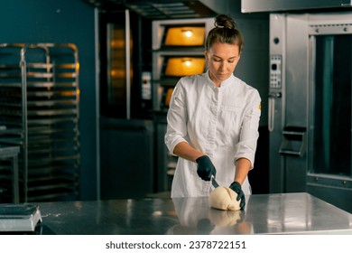 professional female baker in the kitchen forms the dough into a perfect bread shape for sale in the bakery - Powered by Shutterstock