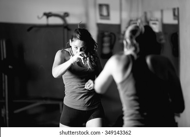 Professional Female Boxer Practicing While Looking In Mirror. Black And White