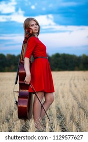 Professional Female Cello Player In Red Dress With Instrument Outdoors