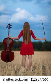 Professional Female Cello Player In Red Dress With Instrument Outdoors