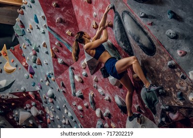 Professional Female Climber On A Bouldering Wall Indoors. 
