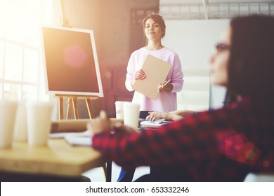 Professional Female Coach Standing Near Flip Chart With Mock Up Area For Your Advertising  Text While Waiting For Questions.Experienced Speaker Woman Conducting Workshop In Studio With Flare Sun