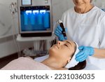 Professional female cosmetologist doing hydra-facial procedure in cosmetology clinic. Doctor using hydra vacuum cleaner. Rejuvenation and cosmetology concept 