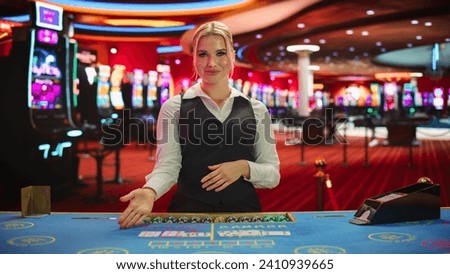 Professional Female Croupier in Casino Dealing Playing Cards on a Baccarat Table. Beautiful Dealer of a Live Online Casino Reveals Winning Results of the Card Game Bets, Looking at Camera