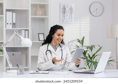 A professional female doctor in a white coat uses a tablet for telemedicine consultation in her bright office, symbolizing healthcare innovation and patient care. - Powered by Shutterstock