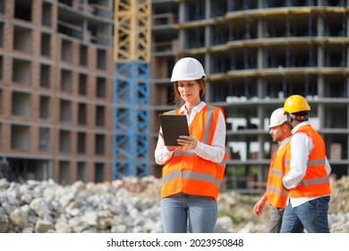 Professional female engineer or architect with tablet stands at construction site with bulldozer on background. - Powered by Shutterstock