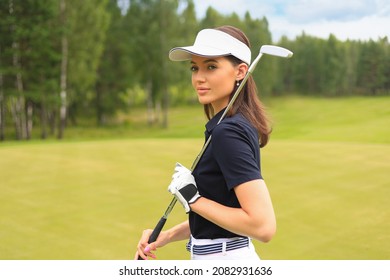 Professional female golfer holding golf club on field and looking away. Young woman standing on golf course on a sunny day. - Powered by Shutterstock