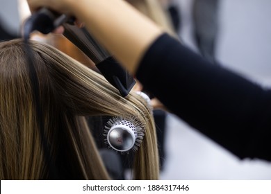 Professional female hairdresser drying woman's hair styling using blow dryer at the hairdressing saloon - Powered by Shutterstock