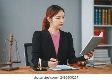 Professional female lawyer reading a book at her desk with legal scales, gavel, and documents. Working in the office with focus and concentration. - Powered by Shutterstock