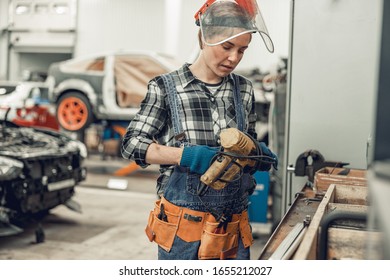 Professional female mechanic holding a power drill in her hand - Powered by Shutterstock