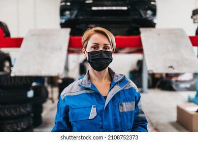 A professional female mechanic with protective face mask working in a car service. - Powered by Shutterstock