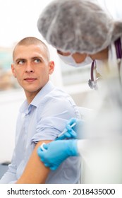 Professional Female Nurse Injecting Vaccine In Shoulder Of Male Patient During Covid Vaccination In Clinic Or Hospital