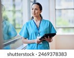 Professional Female Nurse in Scrubs with Digital Tablet at Hospital