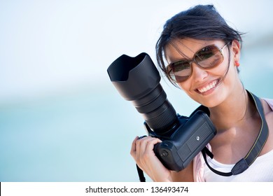 Professional female photographer holding a camera and smiling - Powered by Shutterstock