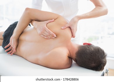 Professional Female Physiotherapist Giving Shoulder Massage To Man In Hospital