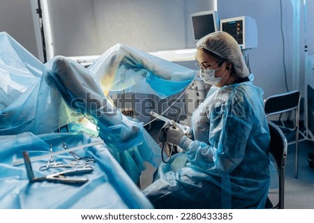 Professional female surgeon proctologist performing operation using special devices for colonoscopy in the operating room in hospital. Urgent surgical concept