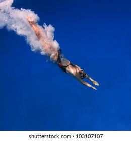 professional female swimmer after jumping with air bubbles trail in blue water