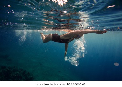 Professional female swimmer swim in the ocean on the sunrise, underwater picture - Powered by Shutterstock