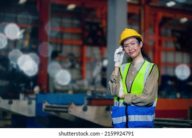 A Professional Female Worker Of African Descent Works To Inspect Machinery In A Manufacturing Plant. Engineer Uniform And Safety Helmet. Copy Space