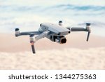 Professional filming drone flies in air at low altitude against blue sky and sea sandy beach. Drone makes photos. Modern new technology. Ready background with place for your text.