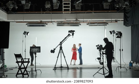 Professional filming pavilion with a white cyclorama. The process of preparing for the shooting of a music video. Director, Cameraman and crew in Backstage. - Powered by Shutterstock