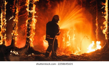 Professional Firefighter Extinguishing Large, High-Priority Part of the Forest Fire. Highly Skilled Hotshot Firemen Working on Challenging Remote Area with Flames Reaching the Treetops.