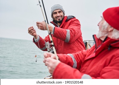 Professional fishing. Waist up portrait view of the unshaven young man telling something to his senior colleague while preparing to the fishing. Stock photo - Powered by Shutterstock