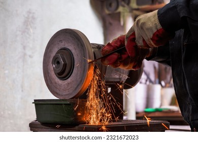 Professional Fitter Man Using Metal Polishing Machine for Metal Rods Sharpening With Sparks in Workshop. Horizontal Image - Powered by Shutterstock