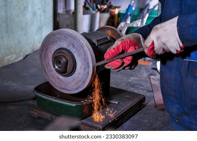 Professional Fitter Man Using Metal Polishing Machine for Metal Rods Sharpening With Sparks in Workshop. Horizontal Shot - Powered by Shutterstock