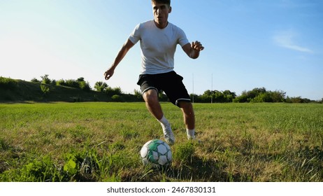 Professional footballer in uniform shows tricks with ball while running at green field. Sportsman kicks ball during jogging at meadow on sunny day. Young man training at stadium. Freestyle football - Powered by Shutterstock