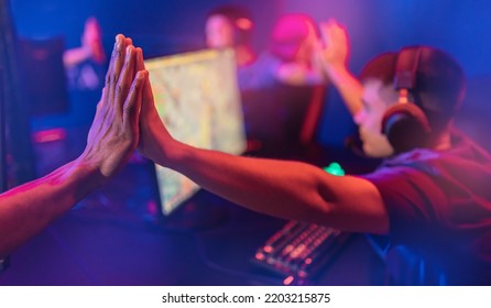 Professional Gamer Greeting And Support Team Fists Hands Online Game In Neon Color Blur Background. Soft Focus, Back View.