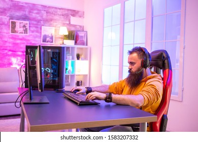 Professional Gamer With Long Beard In Front Of Powerful Gaming Rig In Room Full Of Neon Lights