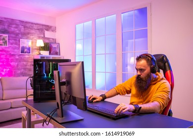 Professional Gamer With Long Beard In Front Of Powerful Gaming Rig In Room Full Of Neon Lights