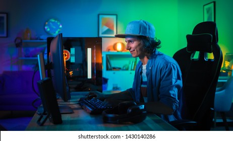 Professional Gamer Playing First-Person Shooter Online Video Game on His Powerful Personal Computer with Colorful Neon Led Lights. Young Man is Wearing a Cap. Living Room Lit with Green Lamps. Evening - Shutterstock ID 1430140286
