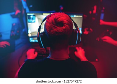 Professional gamer playing online games tournaments pc computer with headphones, Blurred red and blue background. - Shutterstock ID 1527549272
