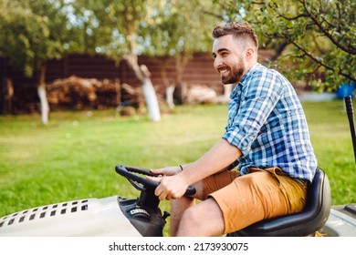 Professional Gardener And Worker Smiling On Ride On Tractor Mowing Lawn And Cutting Grass