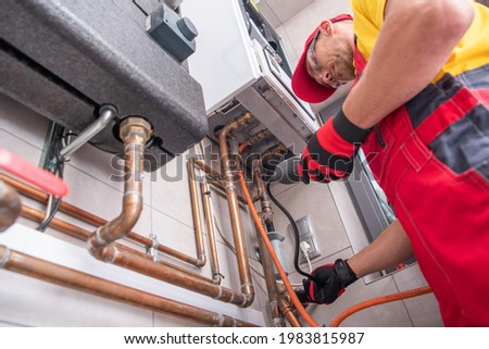 Professional Gas Heating Technician with Natural Gas Detector Device in His Hands Looking For Potential Leaks Inside the Heating Furnace System.