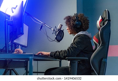 Professional Girl Gamer Plays in Video Game on Her Computer. She's Participating in Online Cyber Games Tournament, Plays at Home, or in Internet Cafe. She Wears Gaming Headset. - Powered by Shutterstock