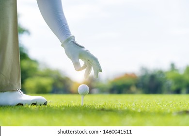 Professional Golf Player hand putting golf ball on tee in golf course - Powered by Shutterstock